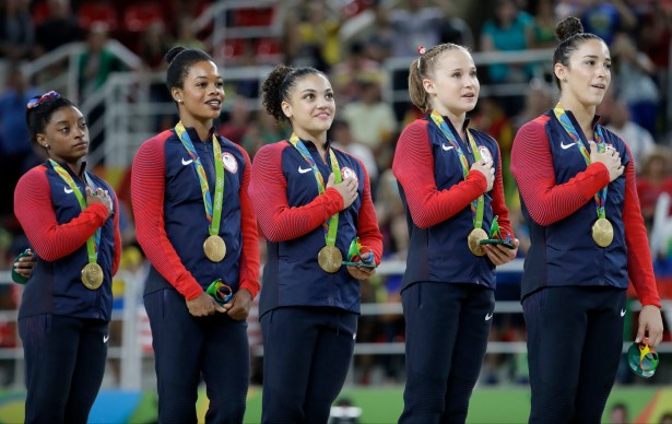 U.S. gymnasts and gold medallists, left to right, Simone Biles, Gabrielle Douglas, Lauren Hernandez, Madison Kocian and Aly Raisman stand for their national anthem during the medal ceremony for the artistic gymnastics women's team at the 2016 Summer Olympics in Rio de Janeiro, Brazil, Tuesday, Aug. 9, 2016.(AP Photo/Julio Cortez)